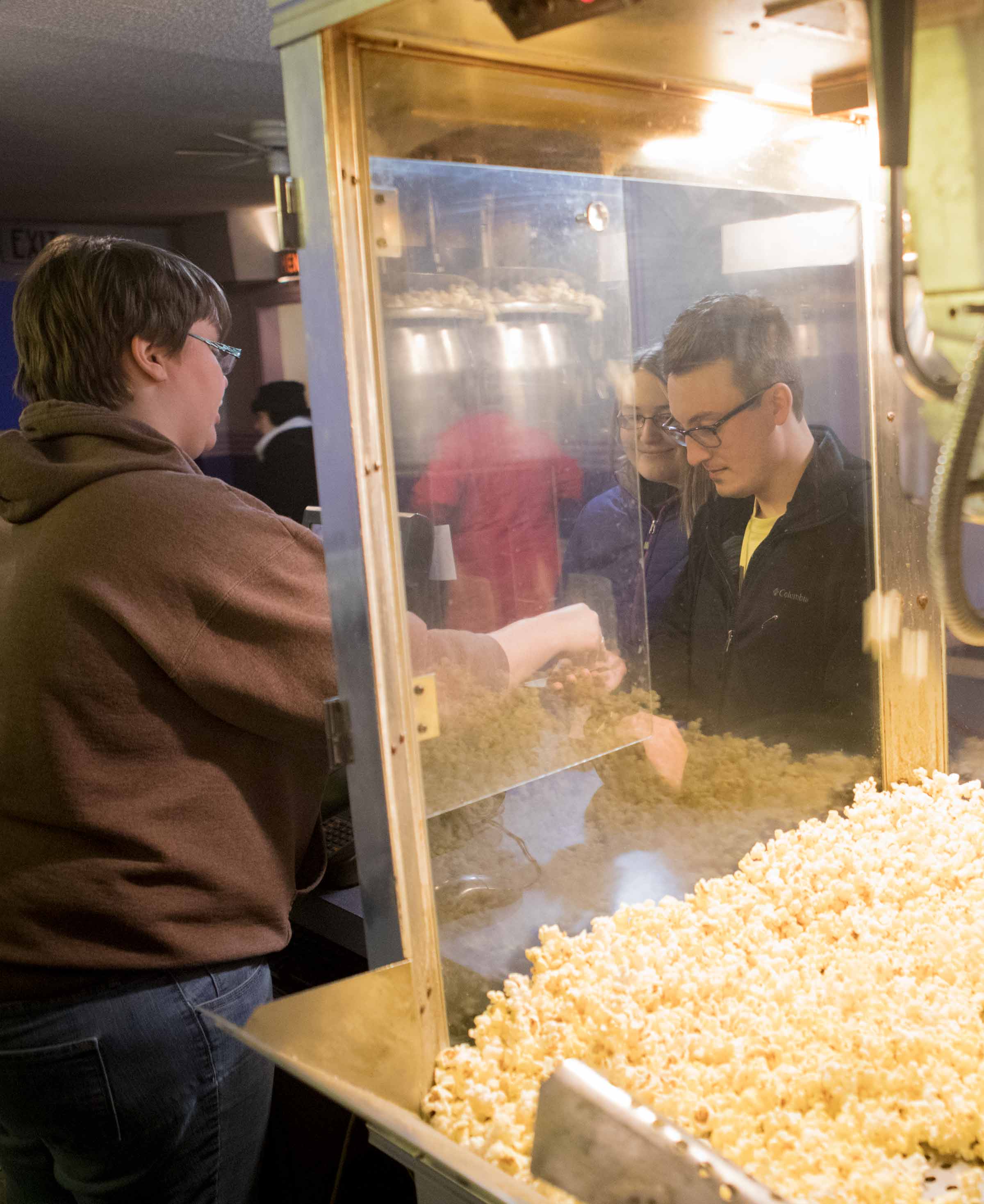 Fifth-year pharmacy student Caitlin Nahirniak and Andy Kremyar, a 2015 «Ӱҵ graduate, buy concessions before the start of a free screening of the movie “Friday Night Lights” at Ada Theatre.