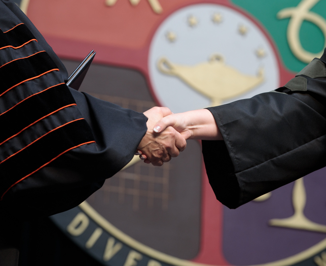 Handshake in front to the «Ӱҵ University seal